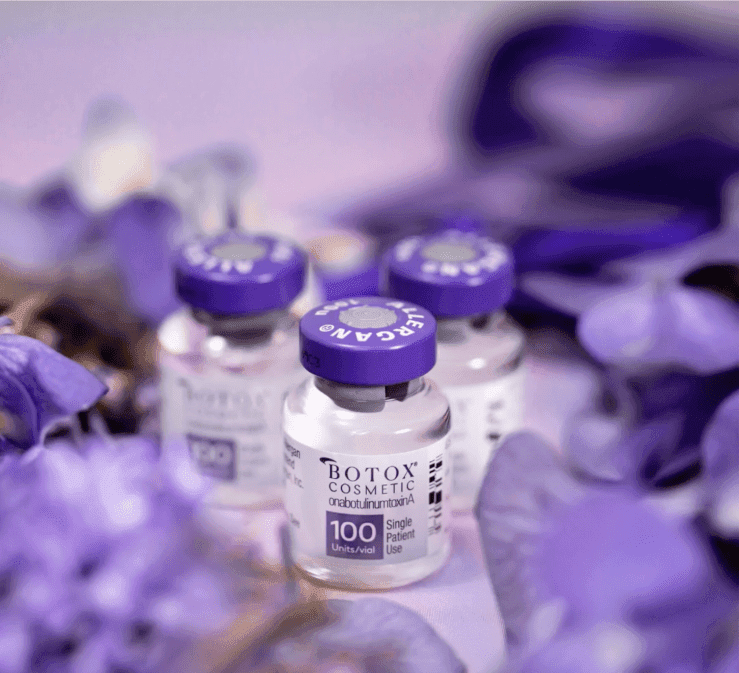 Three vials of Botox Cosmetic with purple caps nestled among soft purple flower petals.